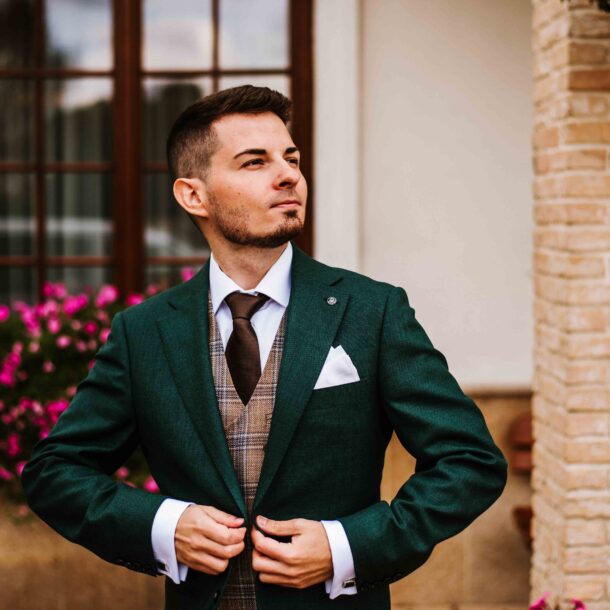 Fotograf ślubny z Lublina w zielonym garniturze przed lokalem weselnym.