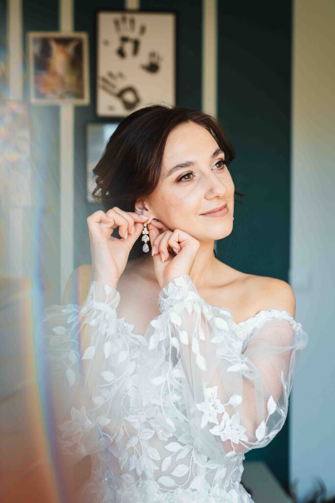 Panna Młoda przymierza kolczyki i suknię ślubną.