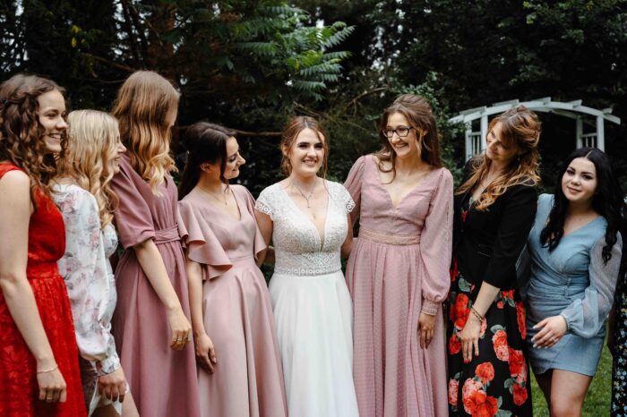 Panna Młoda z przyjaciółkami śmieją się w parku.