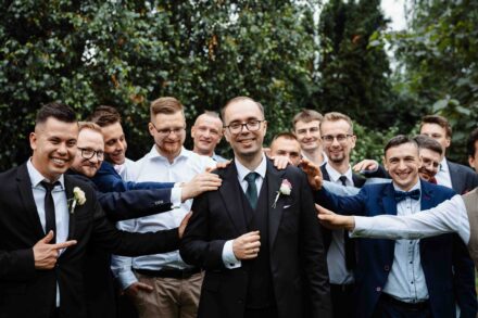 Pan Młody z przyjaciółmi śmieją się w parku.