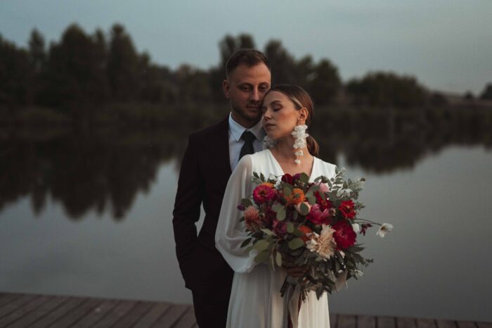 Panna Młoda na molo opiera się plecami o Pana Młodego.