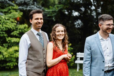 Goście weselny uśmiechają się do fotografa ślubnego w parku podczas wesela.