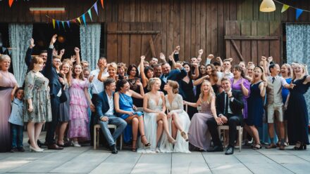 Zdjęcie grupowe gości weselnych przed stodołą.