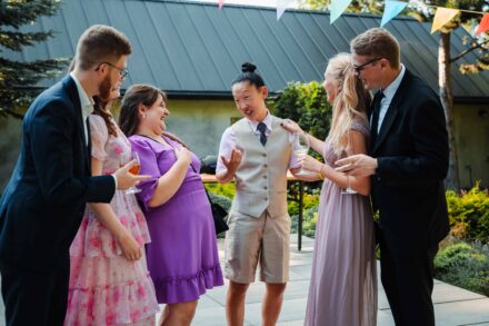 Grupa przyjaciół opowiada sobie żarty podczas wesela i się z tego śmieją.