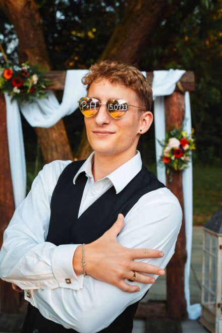 Młody mężczyzna ma nałożone okulary z napisaną datą ślubu. Portret trendującego zwyczaju ślubnego.