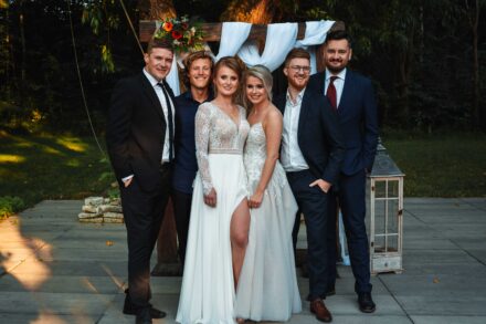 Dwie Panny Młode stoją wśród swoich przyjaciół do zdjęcia grupowego.