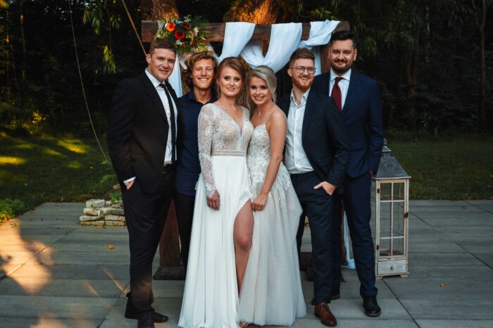 Dwie Panny Młode stoją wśród swoich przyjaciół do zdjęcia grupowego.