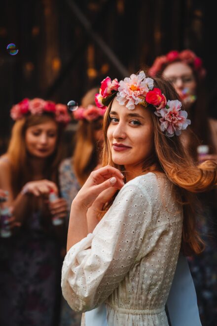 Portret panny młodej w trakcie panieńskiego, podczas gdy druhny puszczają bańki mydlane.