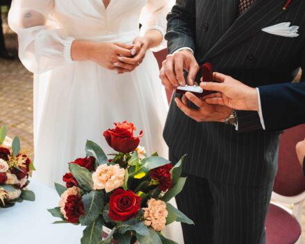 Pan Młody wyciąga obrączki z pudełka, które podaje mu starszy, aby nałożyć obrączkę Pannie Młodej.