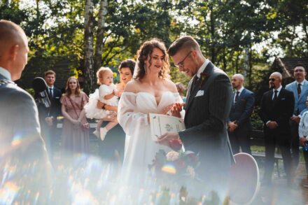 Pan Młody zaraz po ślubie trzyma akt małżeństwa, Panna Młoda i goście klaszczą z radości.